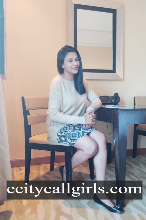 Jyothika in a cream top and printed skirt sitting on a chair in a hotel room, call girl in Electronic City Bangalore